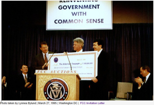 Photograph of President Bill Clinton, Vice President Al Gore, and FCC Chairman Reed Hundt presenting a ceremonial $7.7 billion check in March 1995 from the nation’s first PCS spectrum auction to "The American Taxpayer". Photo taken by Lynnea Bylund.